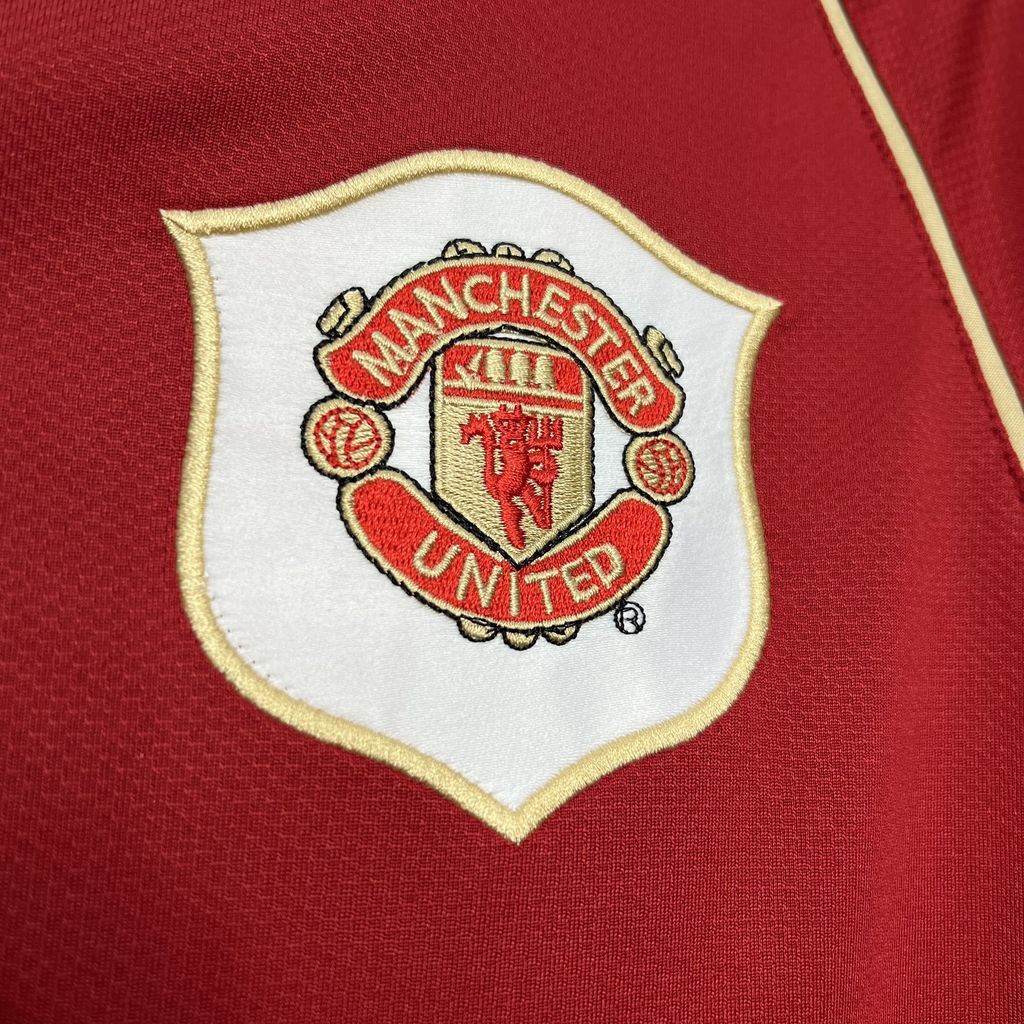 Manchester United crest patch on red jersey with gold border