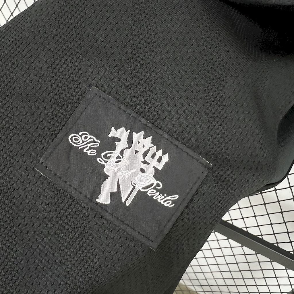 Retro away football jersey fabric tag with white logo on black mesh