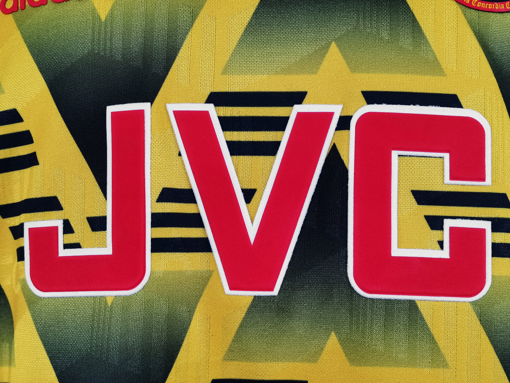 Yellow jersey close-up with red JVC lettering on black zigzag stripes