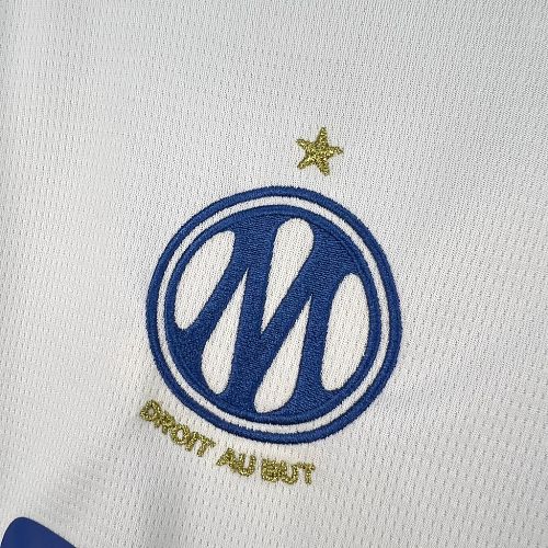 Blue circular club crest with gold star on white football jersey
