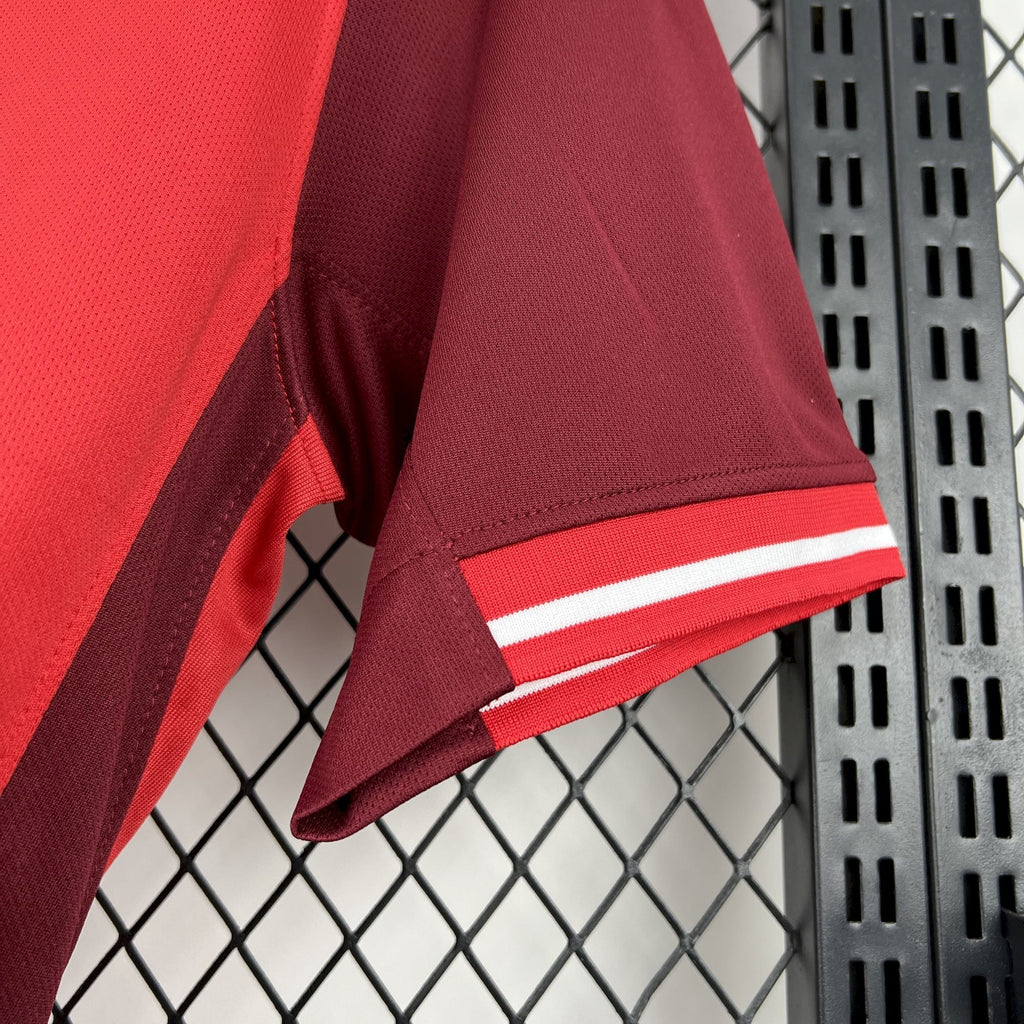 Red soccer jersey sleeve with white striped cuff and dark underarm panel.