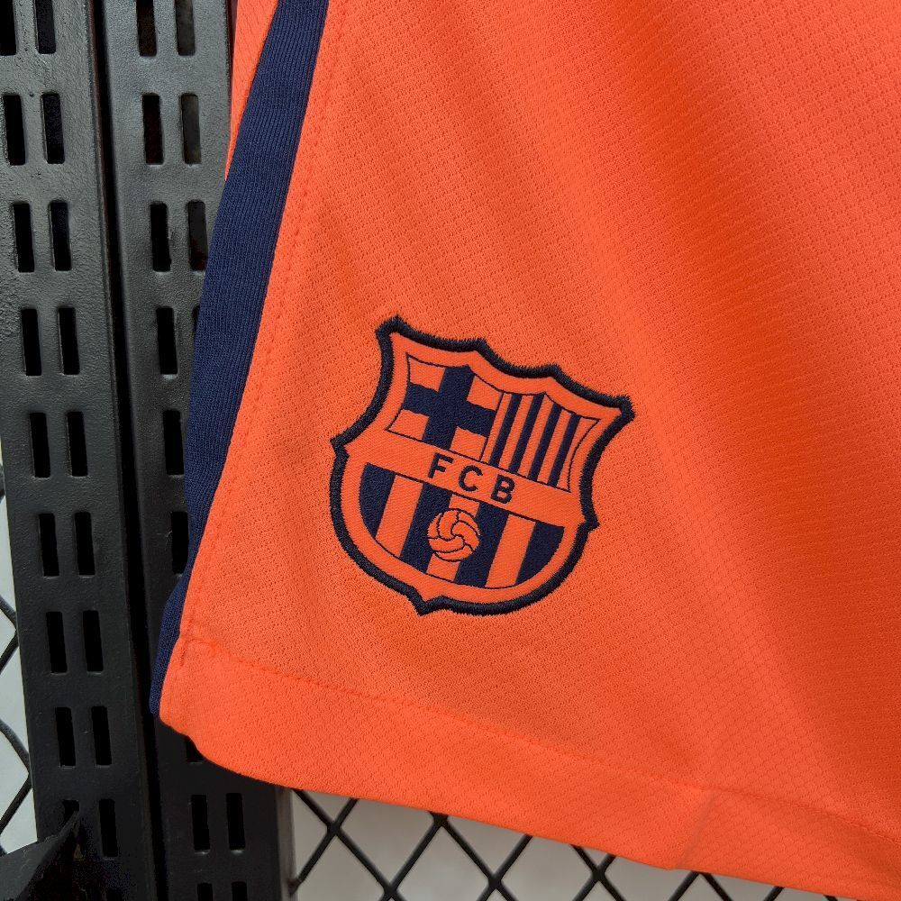 Orange football shorts with FC Barcelona crest badge on hem