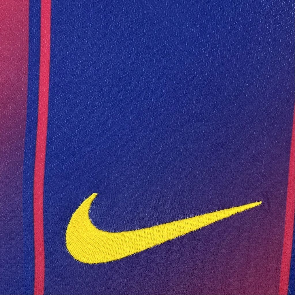 Barcelona home fan football jersey close-up, yellow Nike swoosh on blue-red fabric