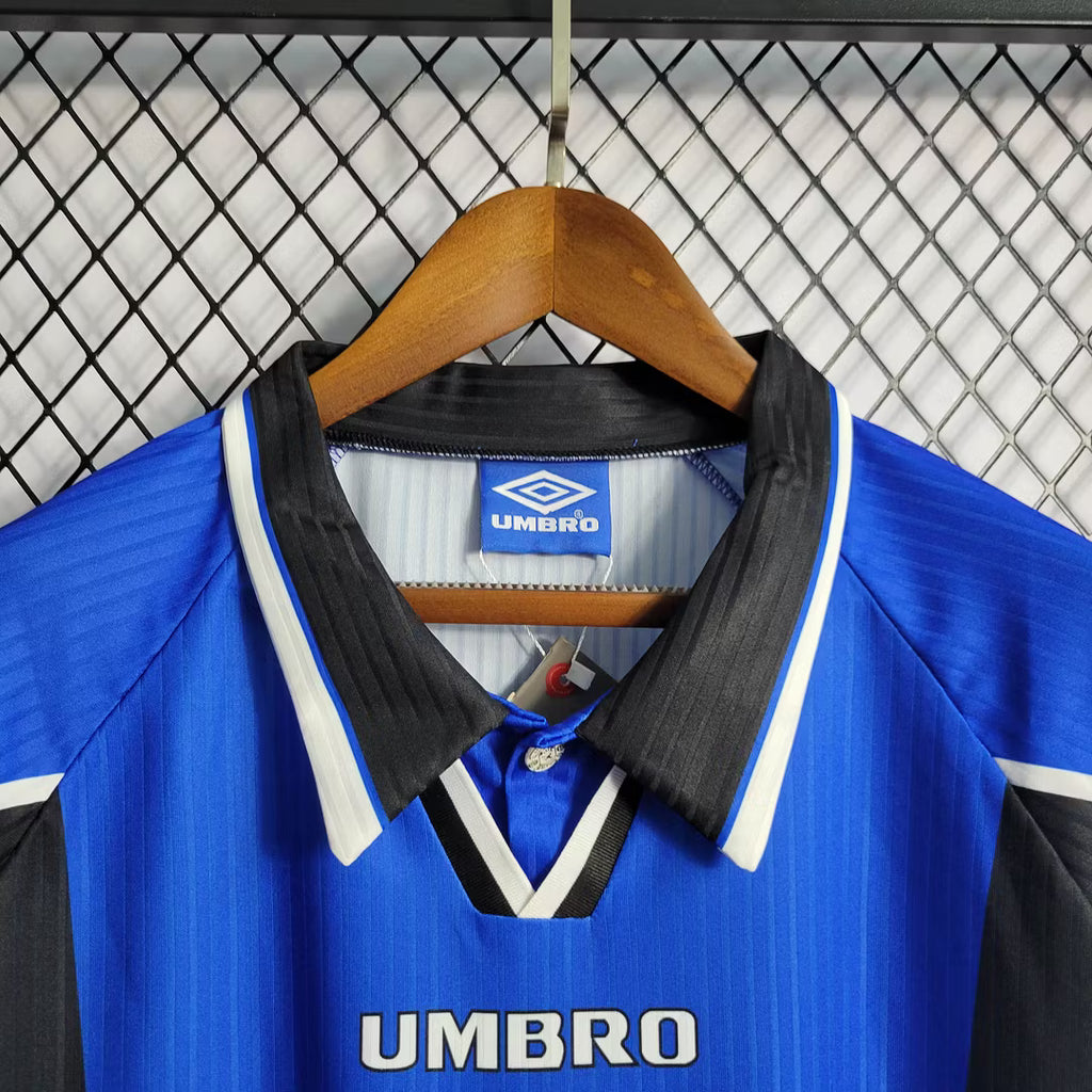 Umbro logo on blue jersey with black-and-white V collar and button placket