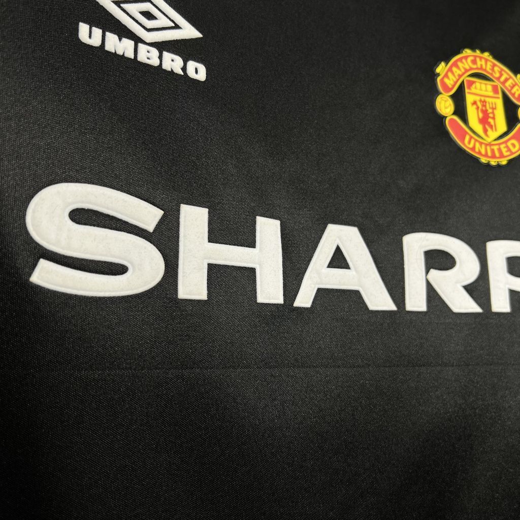 Black soccer jersey close-up: SHARP sponsor print, Umbro mark, club crest