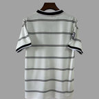 A white short-sleeve t-shirt with thin black horizontal stripes, hanging on a dark wooden hanger against a solid gray background.