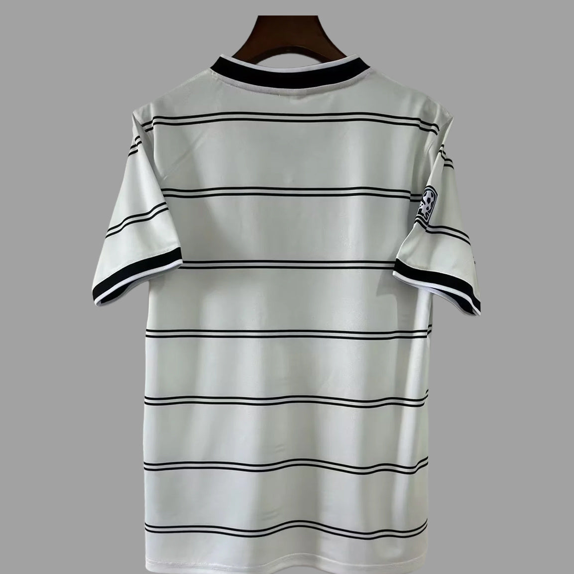 A white short-sleeve t-shirt with thin black horizontal stripes, hanging on a dark wooden hanger against a solid gray background.