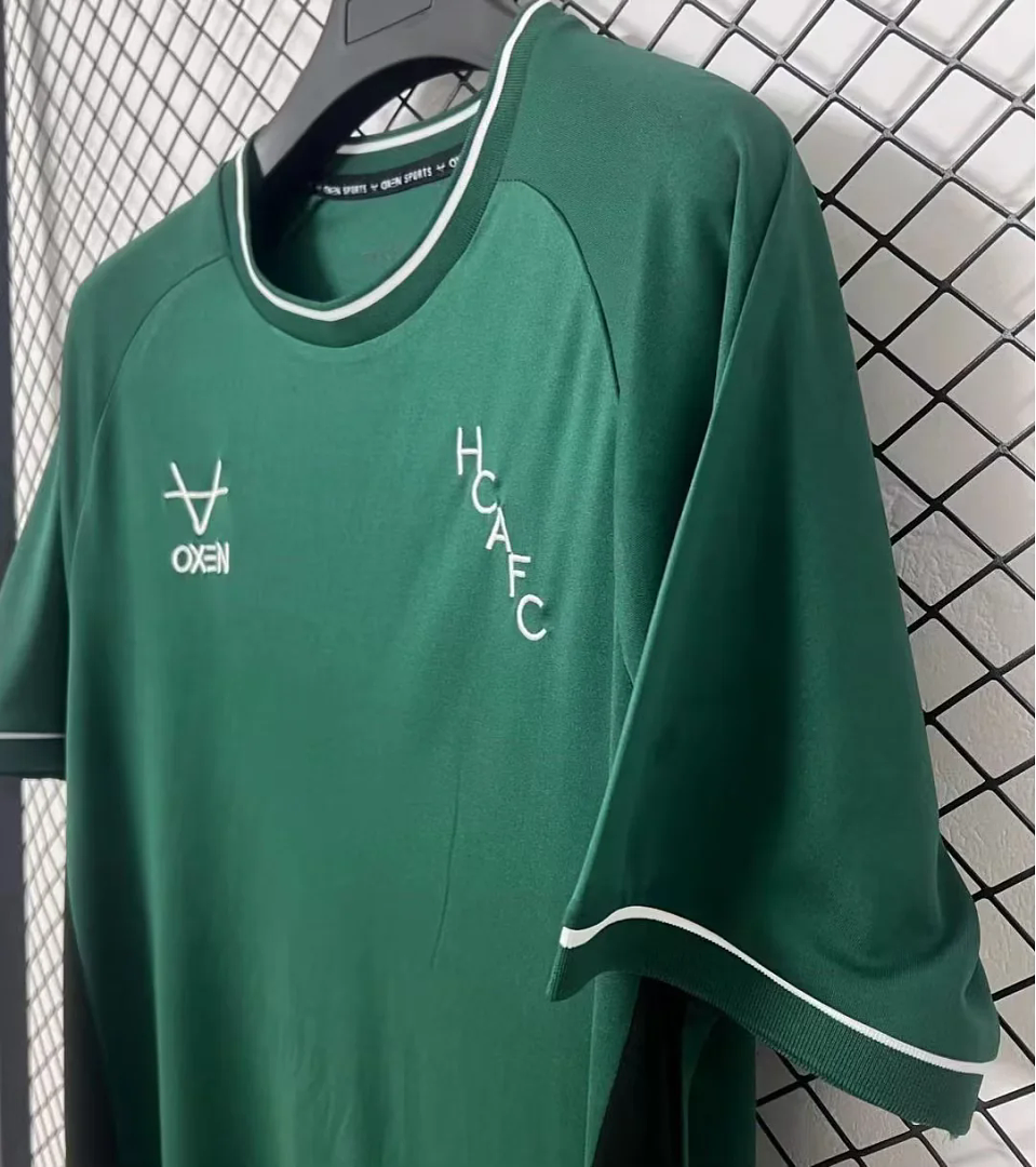 Green goalkeeper fan jersey close-up with OXEN mark and HCAF FC crest
