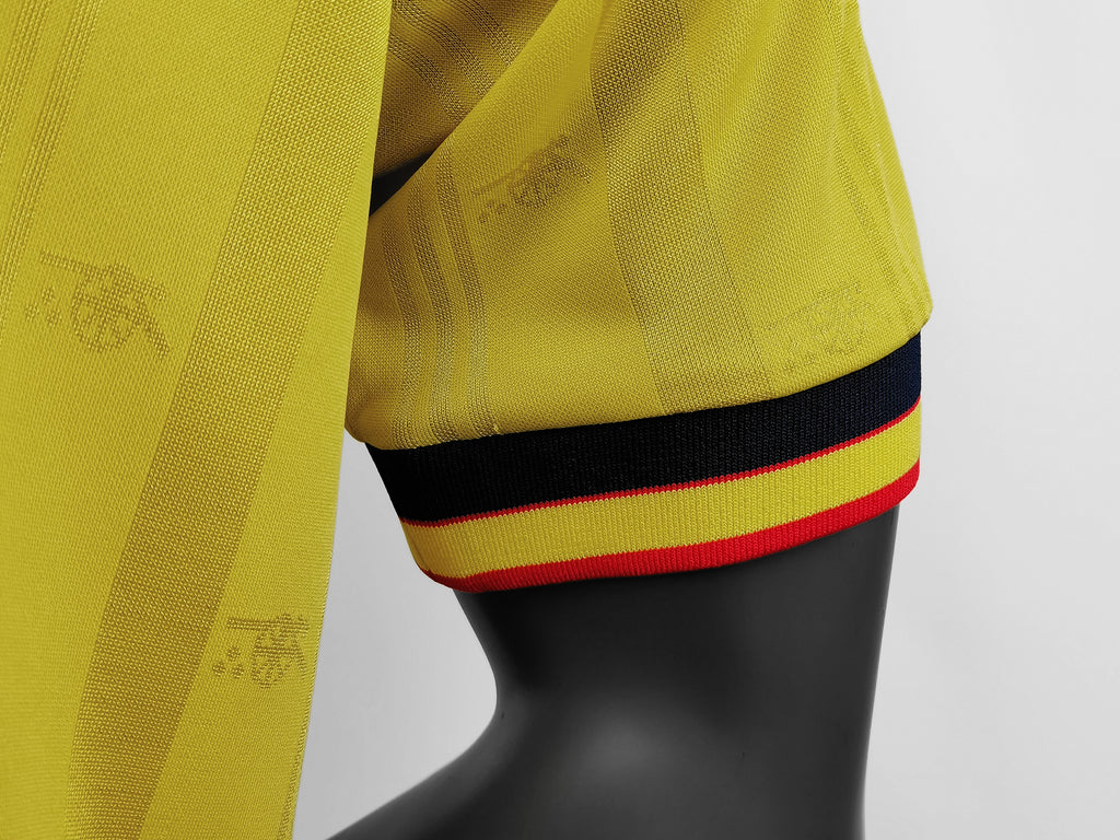 Yellow jersey sleeve cuff with navy band and red-and-yellow striped trim at hem