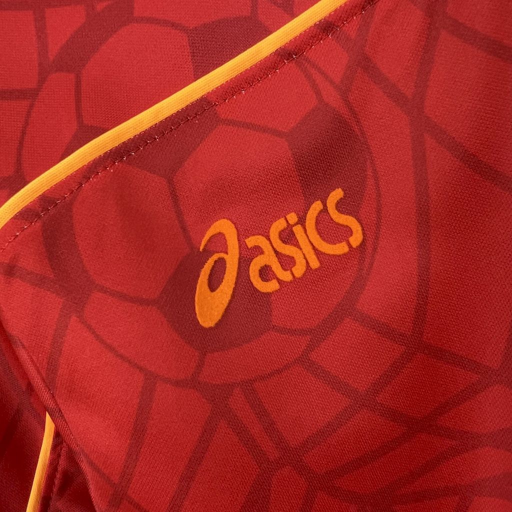 Red jersey fabric close-up with orange asics logo.