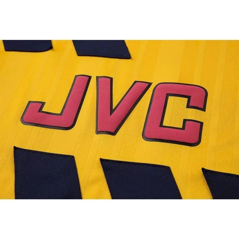 Yellow retro football jersey close-up of JVC sponsor text in red outline and navy