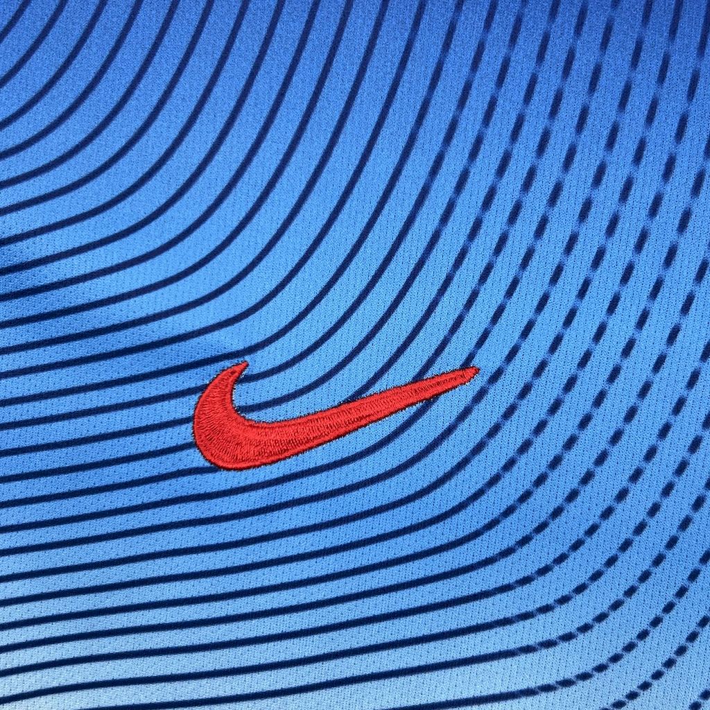 Red Nike swoosh logo on blue retro jersey with ripple stripe pattern