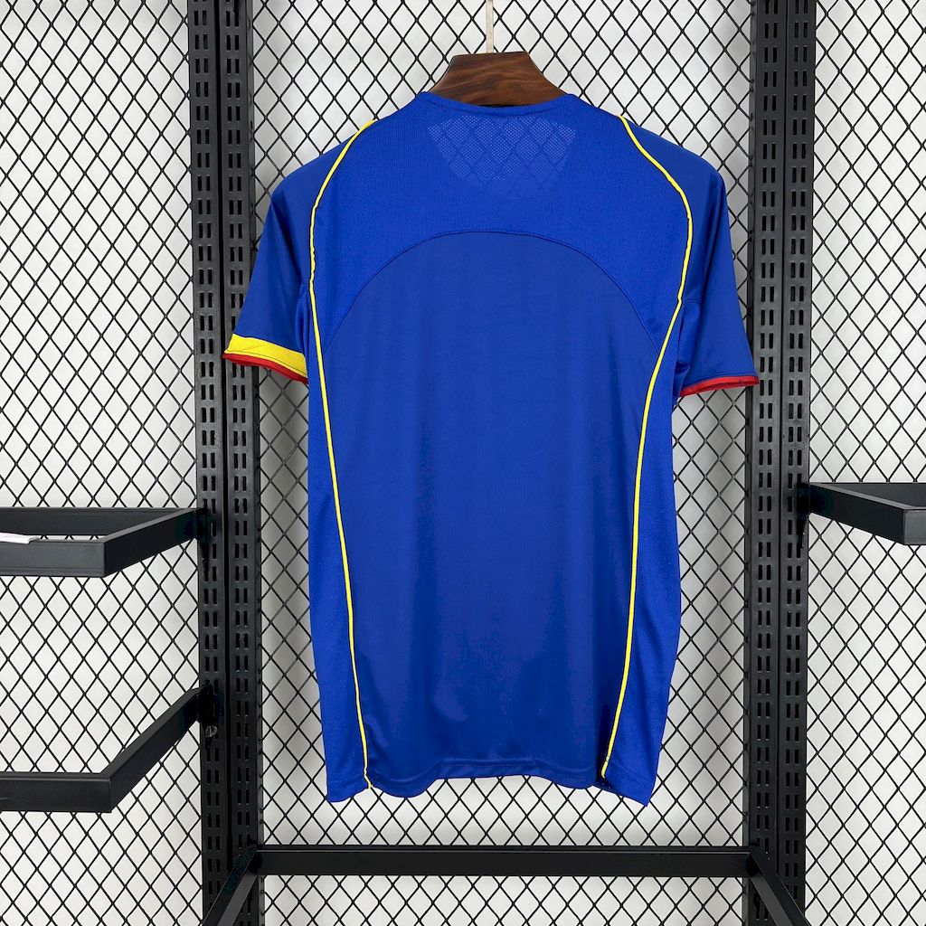 Blue football jersey back view with yellow piping and red trim at cuffs