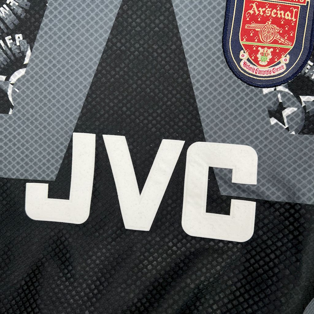 Black goalkeeper jersey chest close-up with JVC logo and Arsenal crest badge
