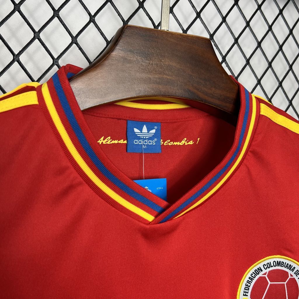 Red jersey neckline with striped V trim, Adidas tag, and small circular crest