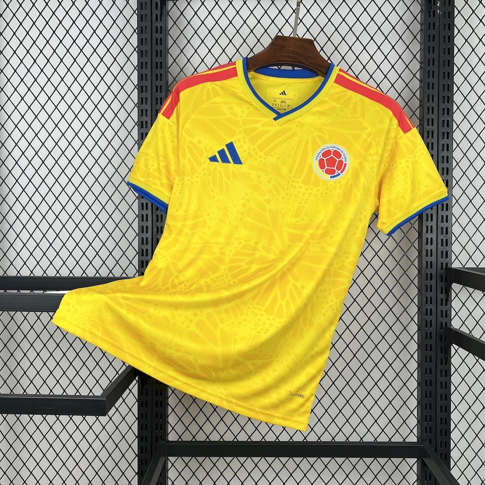 Yellow Colombia home soccer jersey, short sleeves, blue V-neck collar, red shoulder stripes.