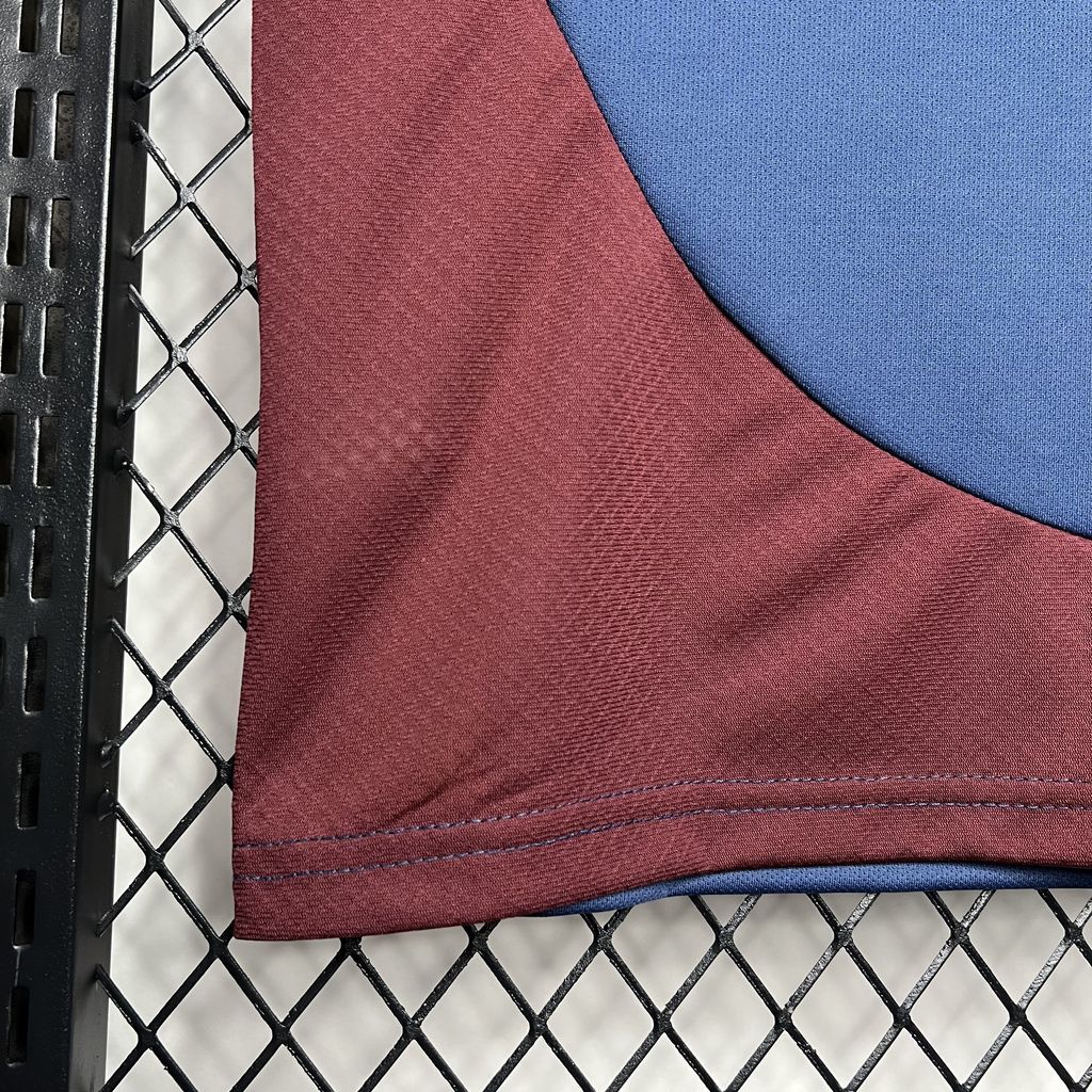 Close-up of maroon and blue jersey sleeve with stitched hem and blue seam