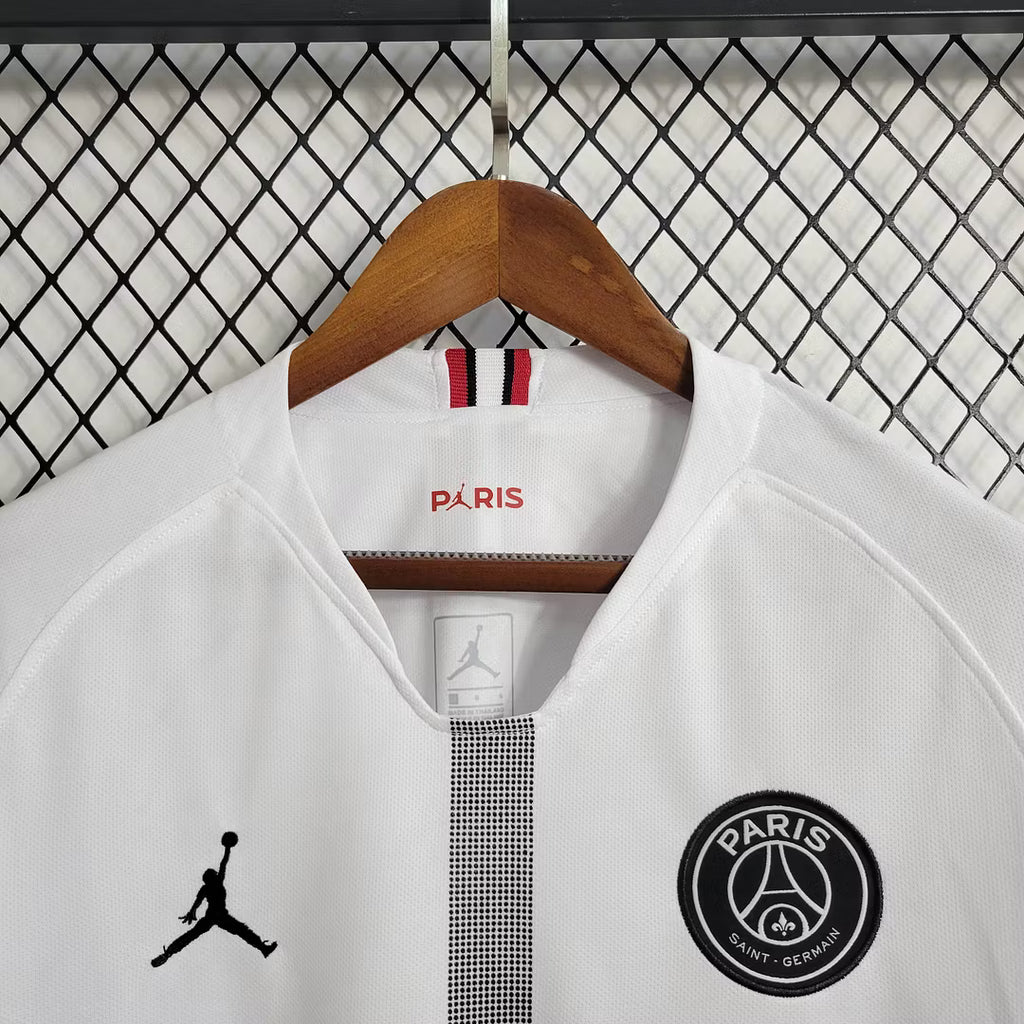 White PSG long-sleeve soccer jersey close-up with Paris logo, Jordan emblem, and PSG crest