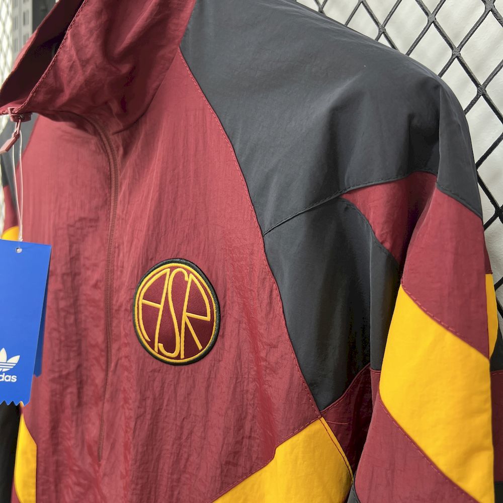 Maroon windbreaker with round crest logo and black/yellow geometric panels, full-zip collar.