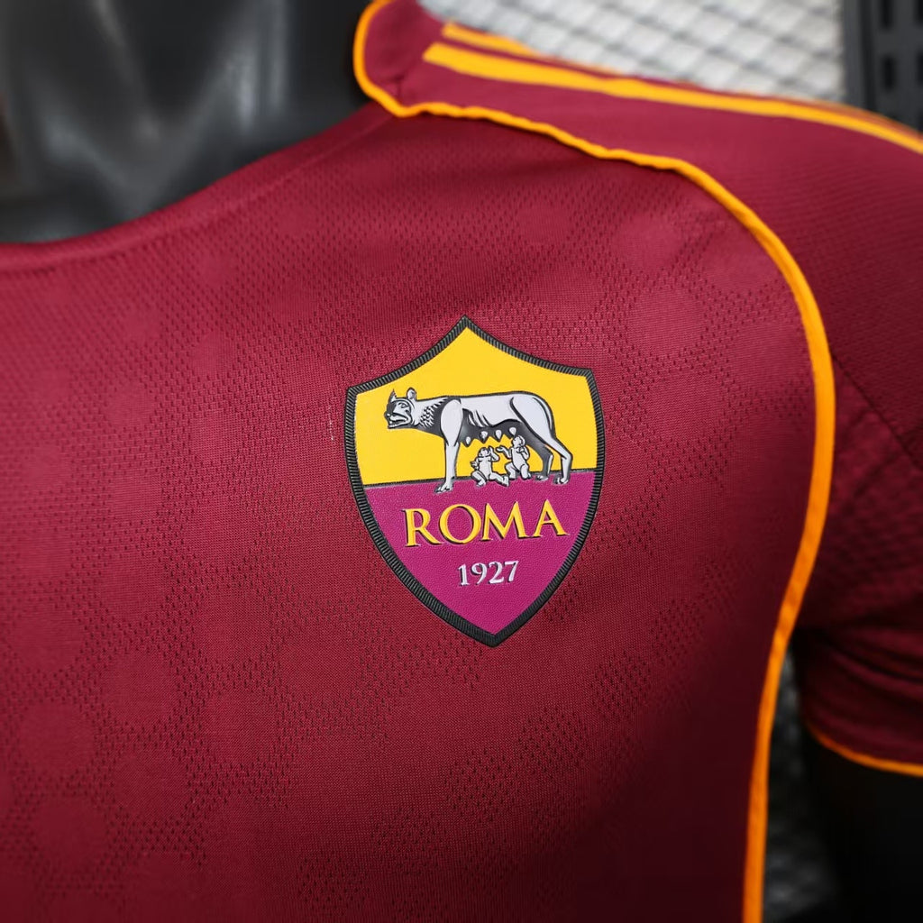 Maroon jersey chest crest with gold border and “ROMA 1927” text.