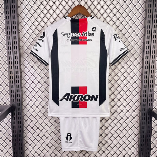 Kids away soccer kit: white jersey with red center stripe, dark blue side panels, matching shorts