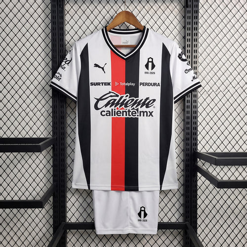 Kids away soccer kit: white jersey with red center stripe, black trim, matching shorts