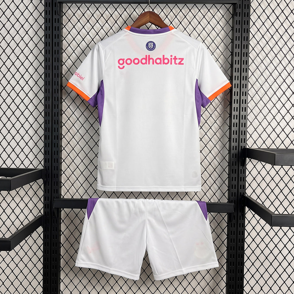Kids away football kit: white back jersey with purple sleeves and orange trim, matching white shorts