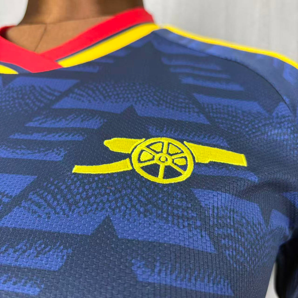 Women’s dark blue Arsenal away soccer jersey close-up, yellow cannon emblem on chest