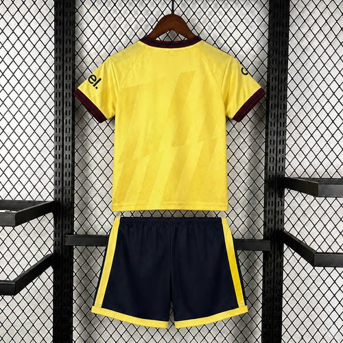 Kids yellow football kit from back: jersey with red cuffs, navy shorts with trim