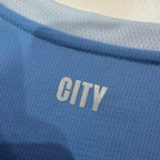 Light blue jersey collar area with embroidered "CITY" text