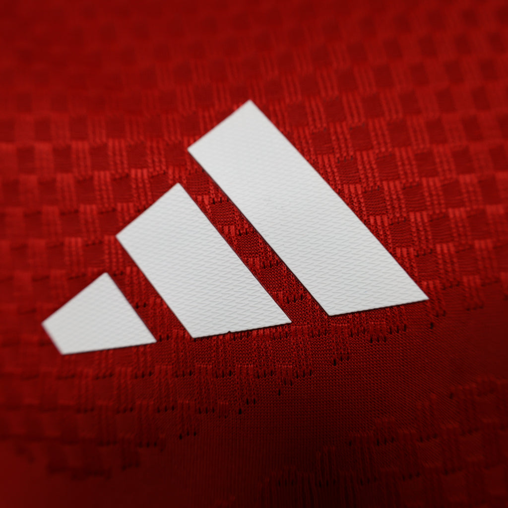 Arsenal home football jersey adidas triple stripes logo on red textured fabric