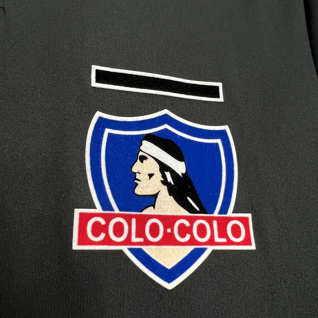 Colo-Colo shield crest with blue border and red 'Colo-Colo' text on black jersey