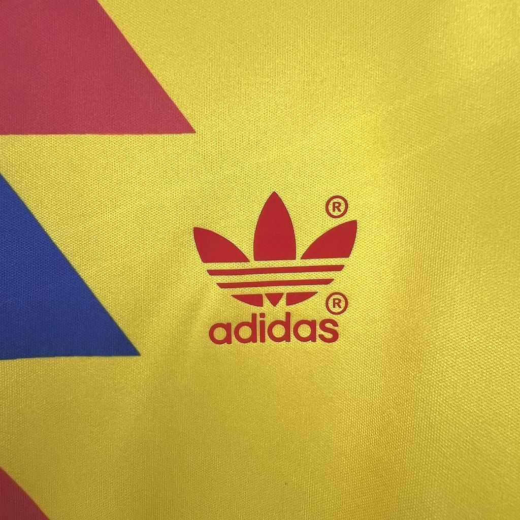 adidas trefoil logo on yellow soccer jersey with maroon, blue, and red stripes