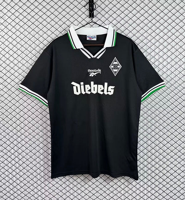 Black retro soccer jersey with white V-neck, green trim, sponsor and crest