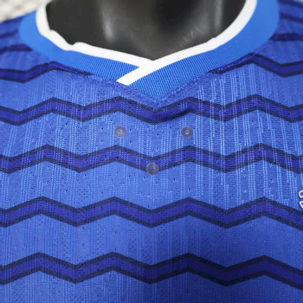 Blue home soccer jersey with zigzag chevron pattern and button placket