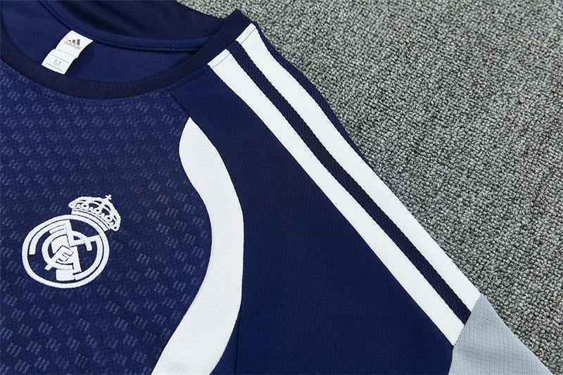 Navy training jersey shoulder with white stripes and Real Madrid crest.
