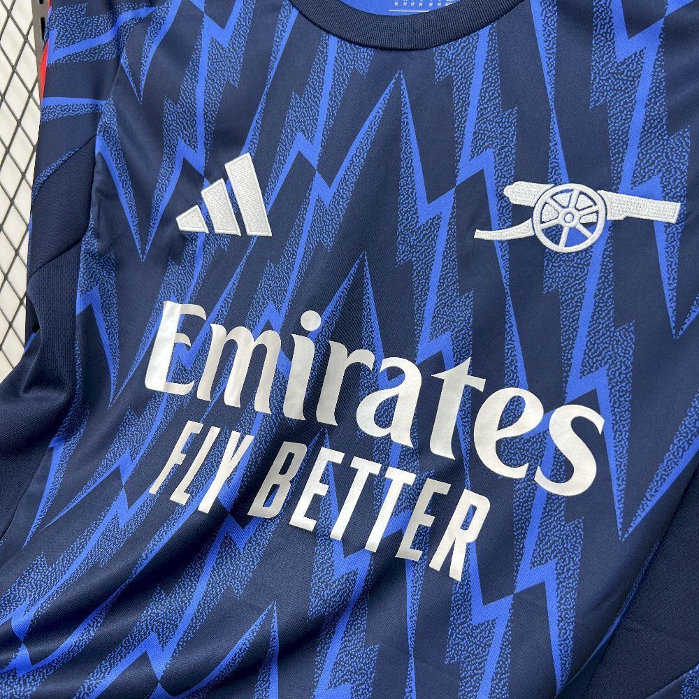 Blue long-sleeve jersey close-up with Emirates Fly Better text and zigzag pattern