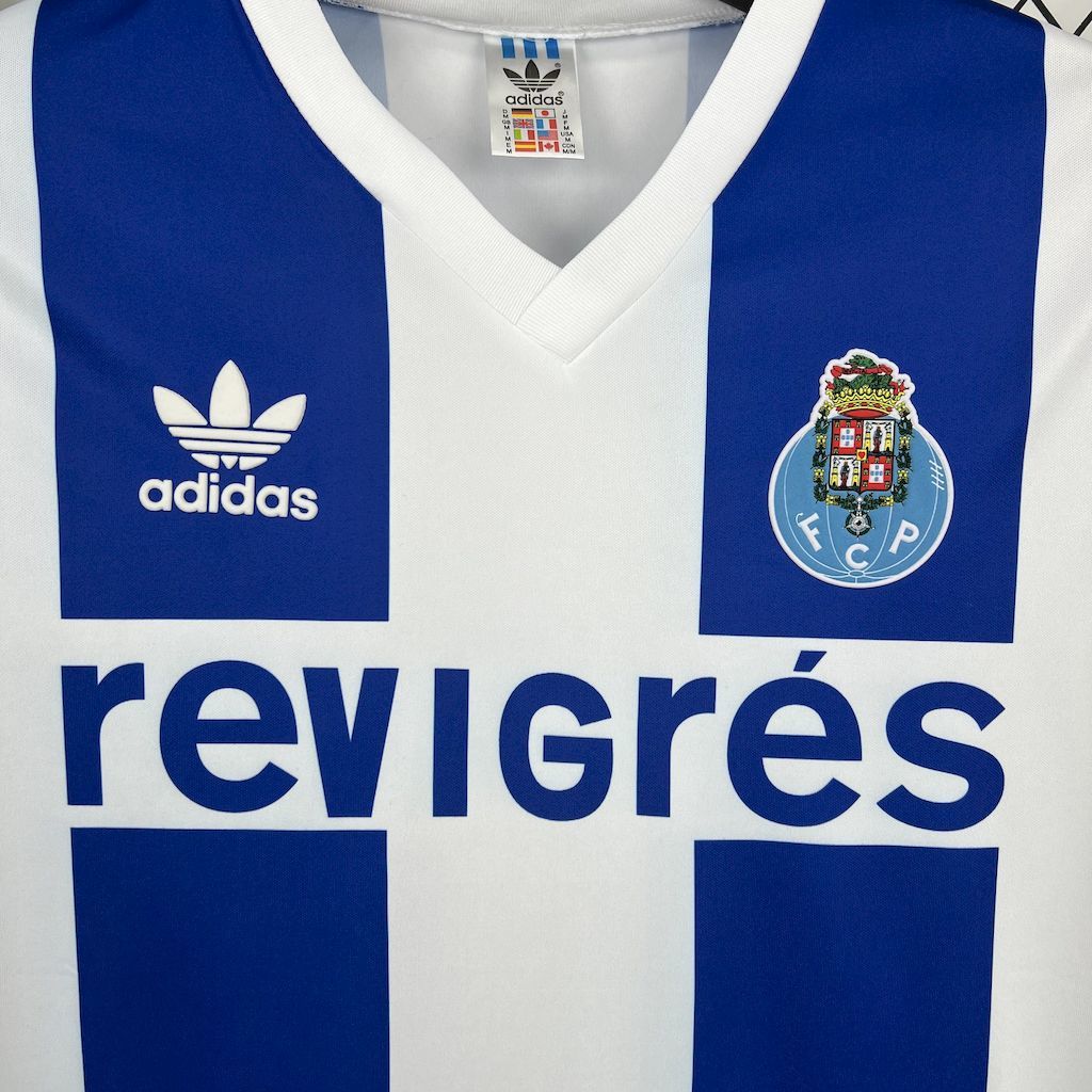 Close-up of blue/white V-neck retro jersey with adidas logo, crest, and sponsor lettering