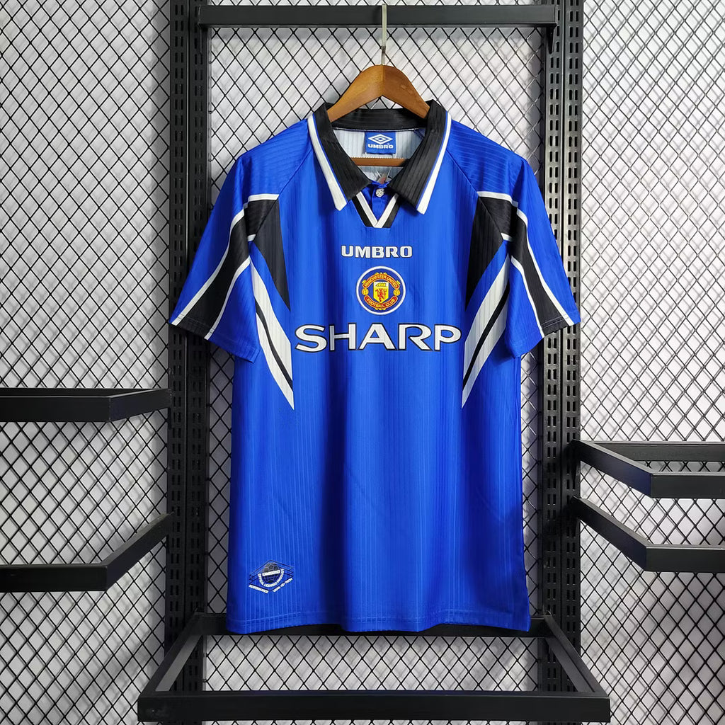 Blue retro soccer jersey with black collar, white trim, Manchester United crest and SHARP
