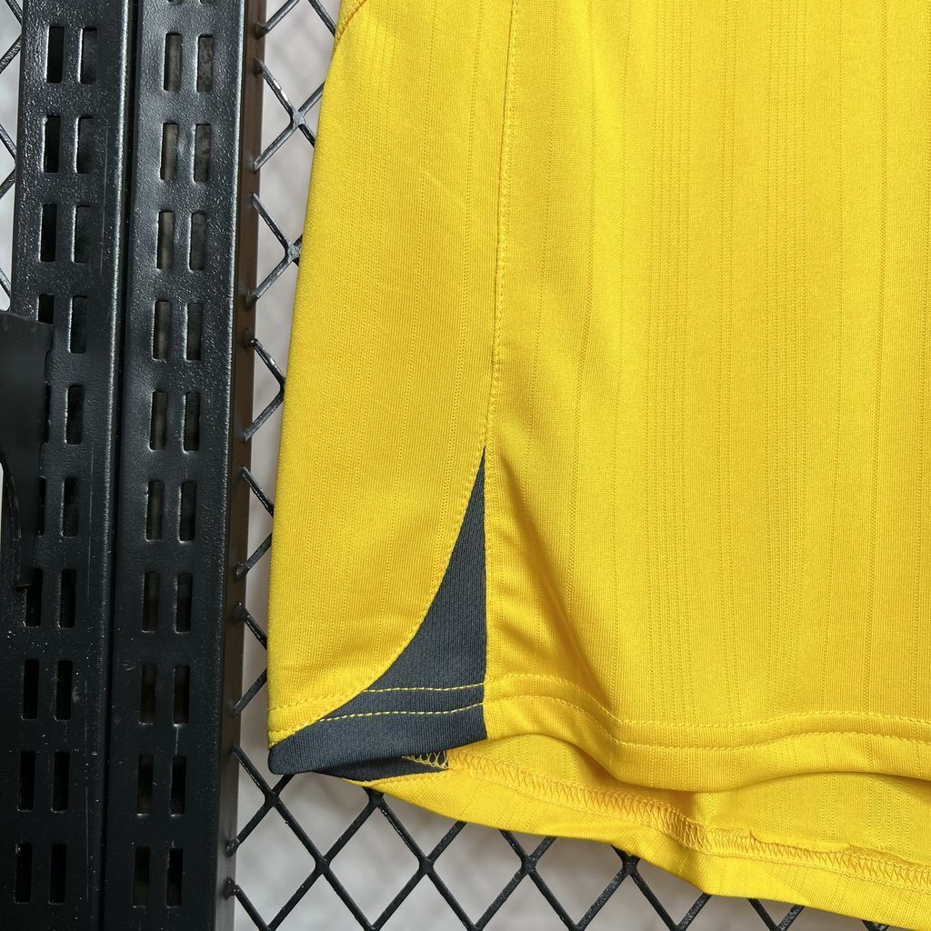Yellow football jersey hem and side panel detail with dark trim and stitching