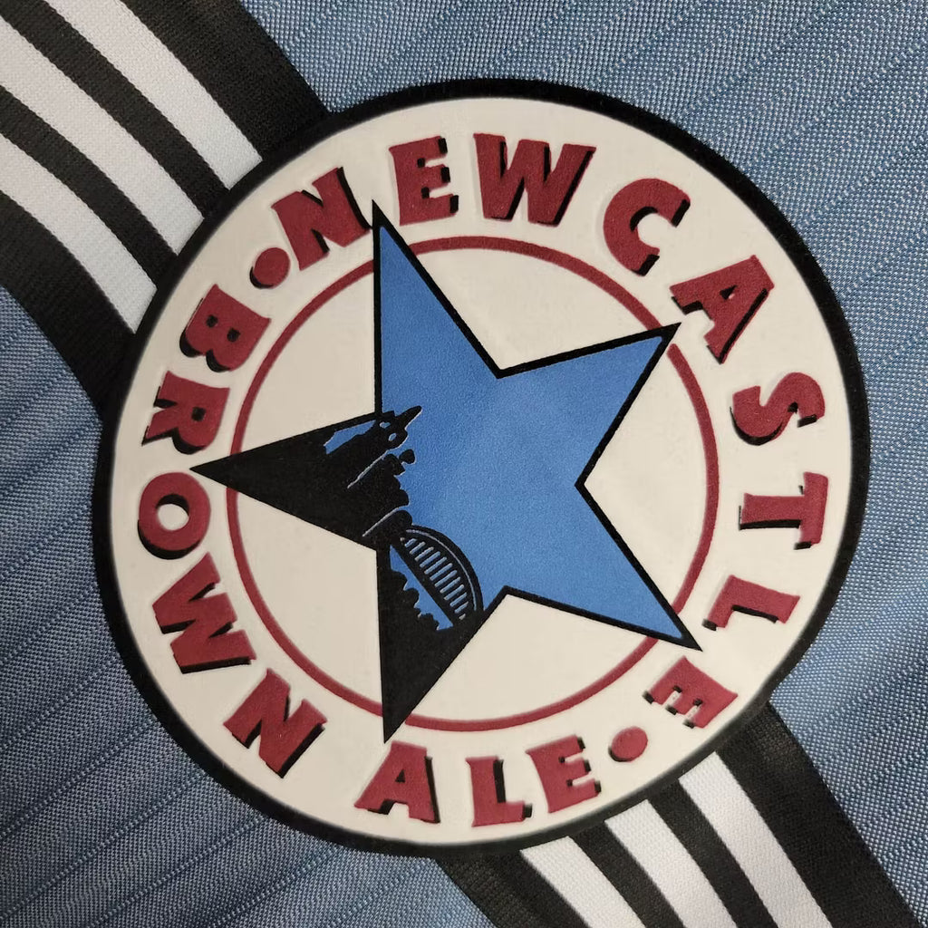 Round sponsor patch with blue star and red text on black-and-white striped jersey