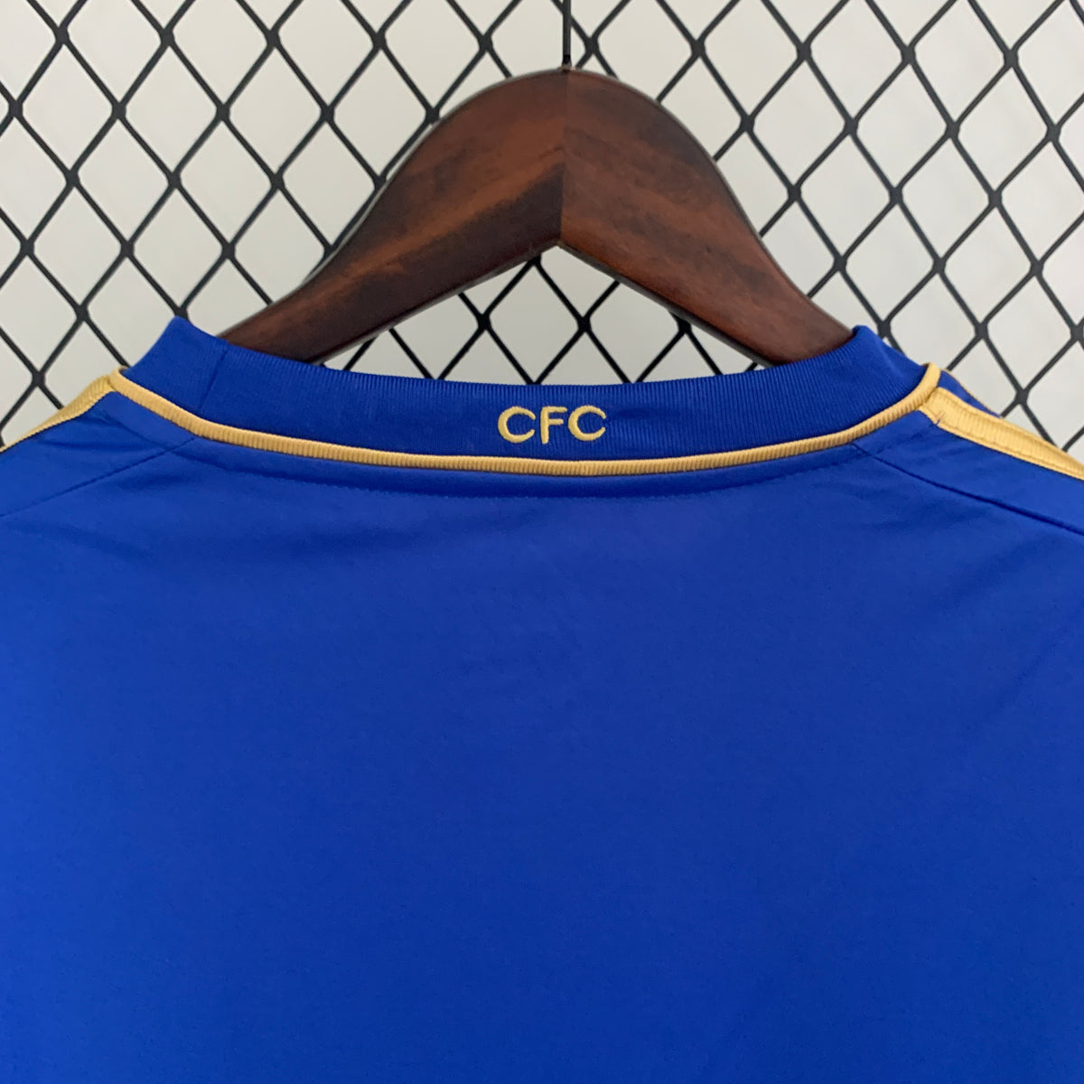Blue soccer jersey collar with gold CFC text and orange piping