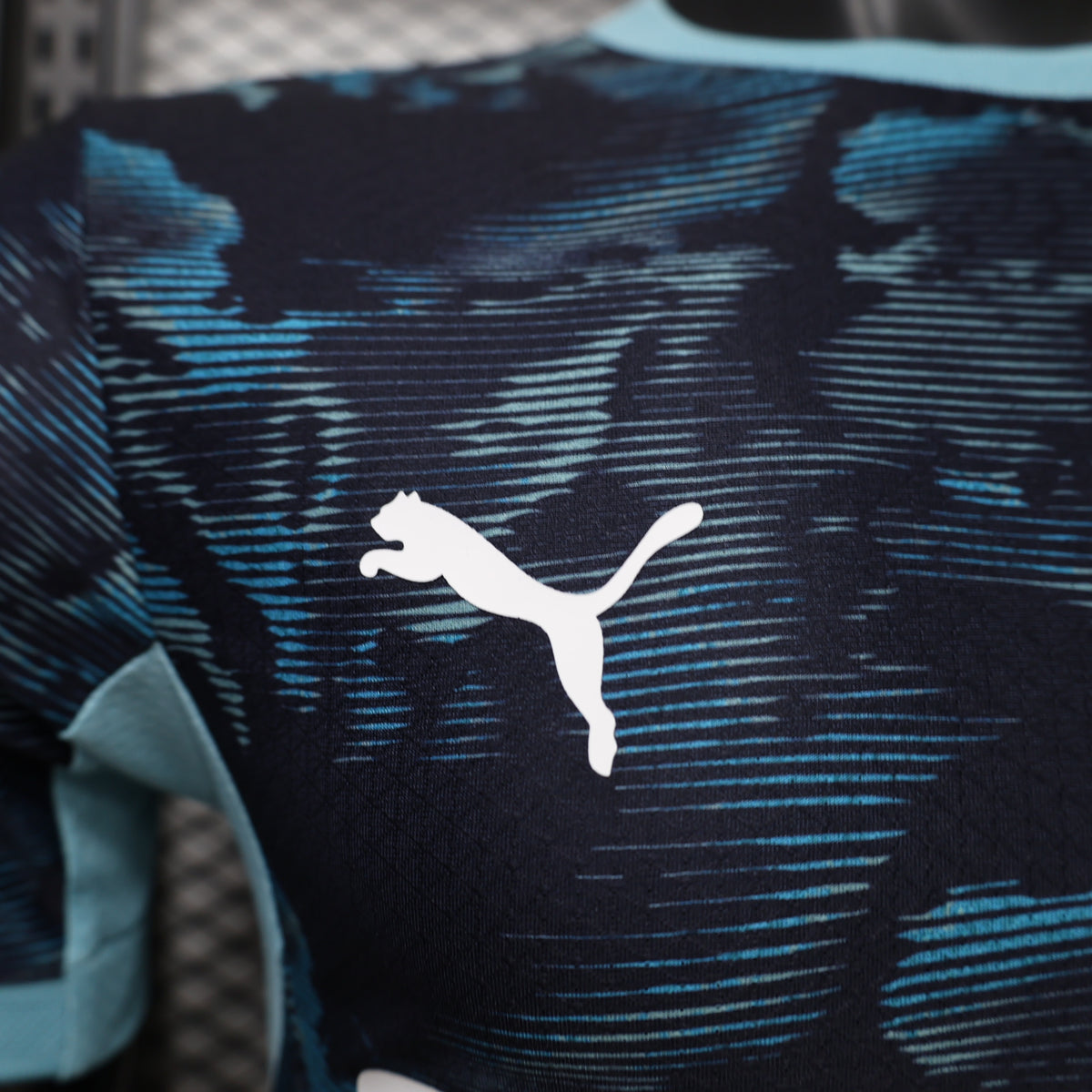 Dark navy soccer jersey with blue camo pattern and white Puma logo on chest.
