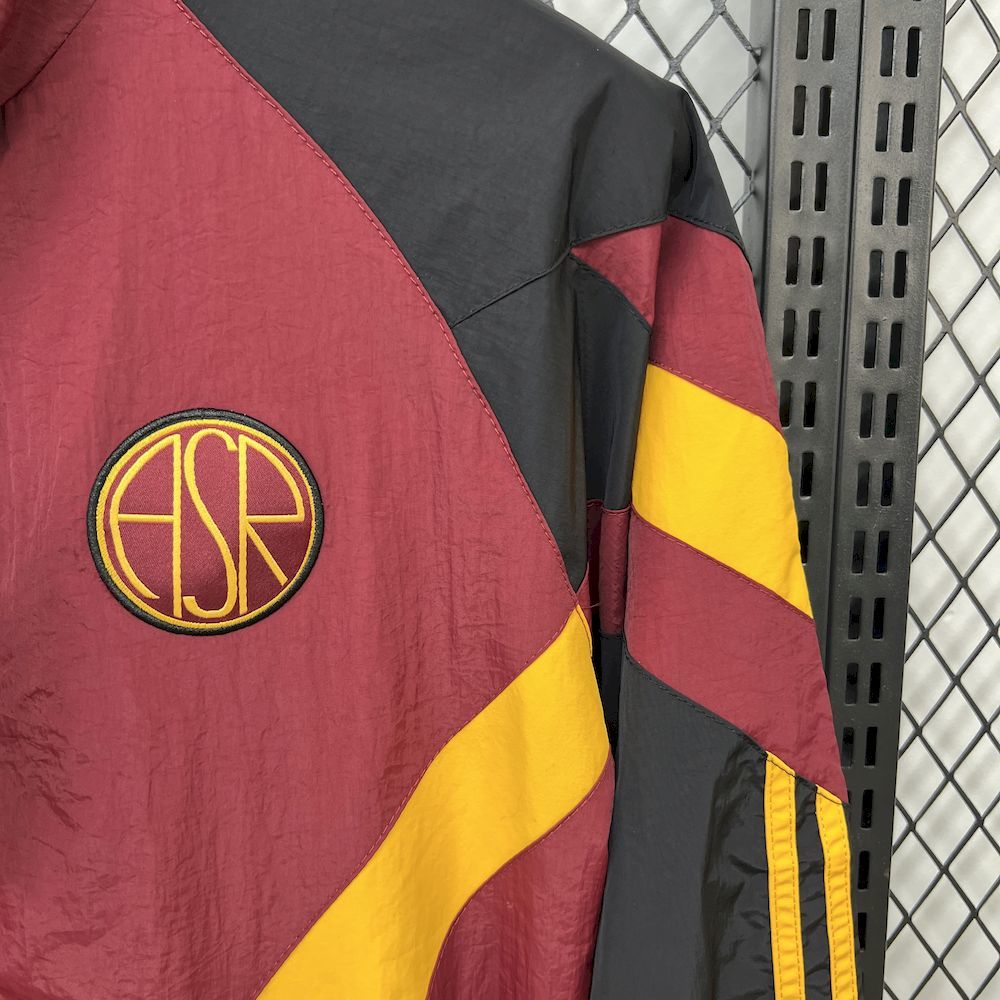 Maroon windbreaker with round crest emblem, black paneling and yellow sleeve stripes.