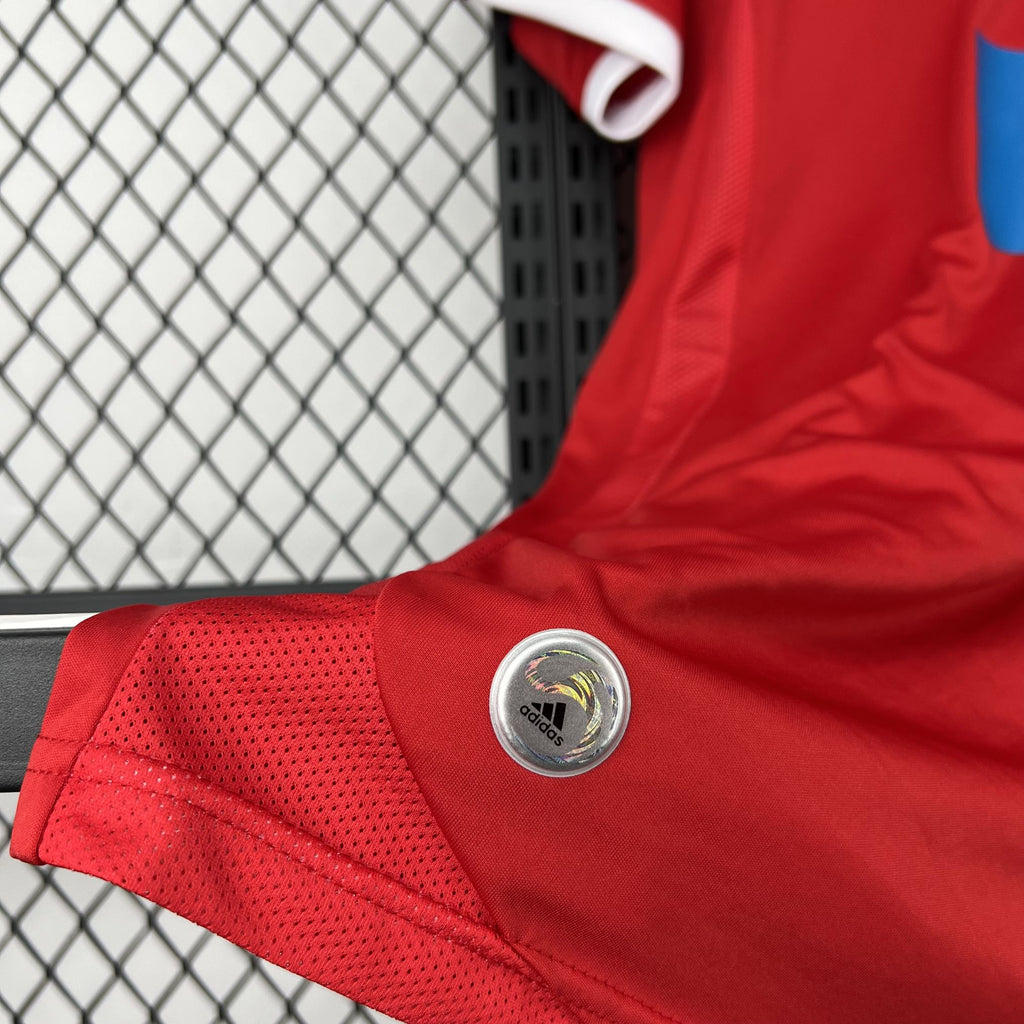 Red soccer jersey sleeve with adidas circular badge and perforated texture