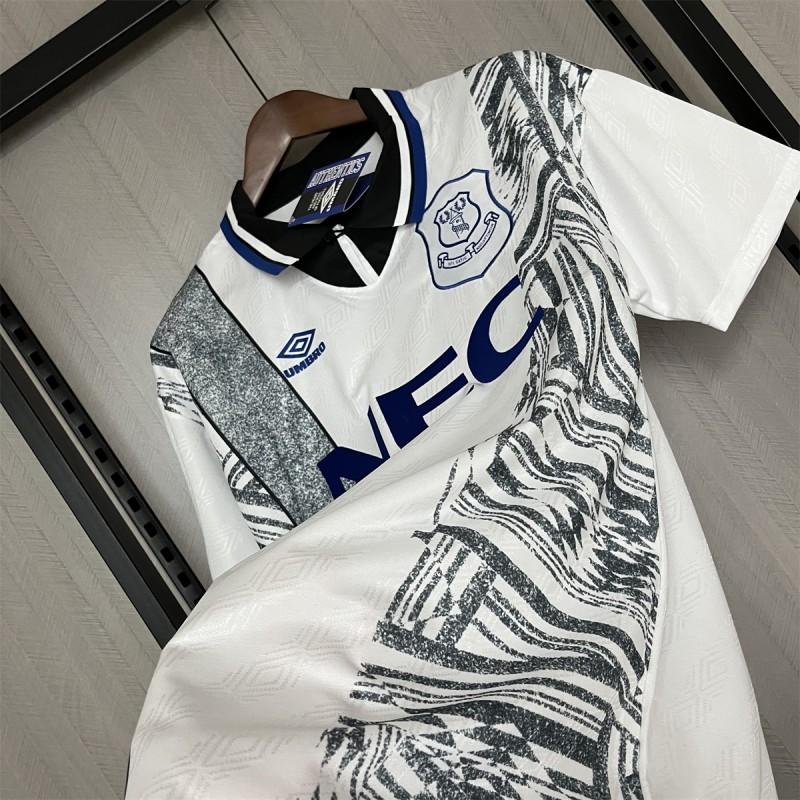 Retro away football jersey laid out, white base with black brush pattern and blue trim