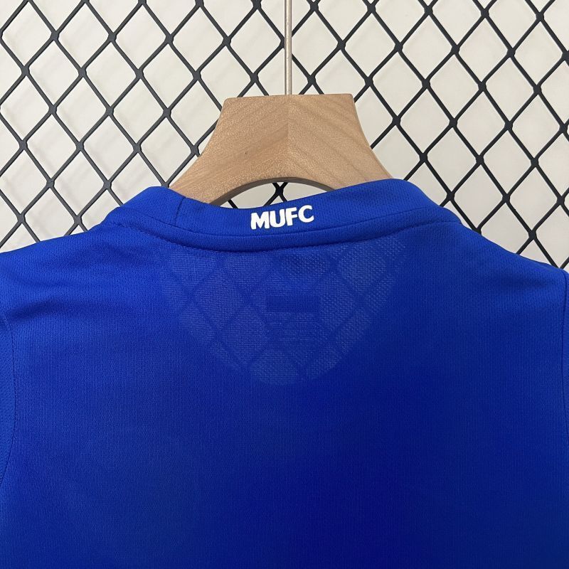 Blue kids MUFC jersey close-up at the collar, showing textured fabric