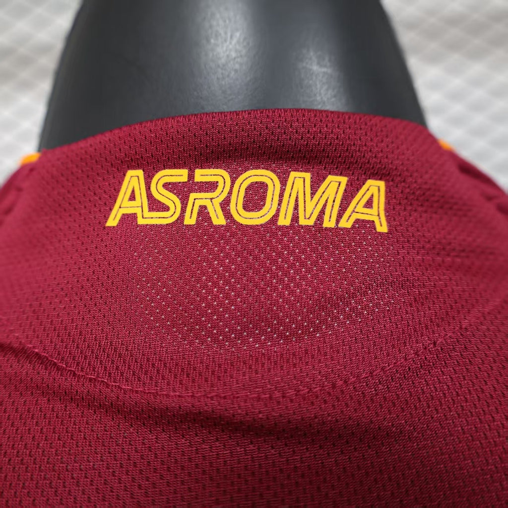 Maroon jersey fabric detail with yellow “ASROMA” lettering across the chest.