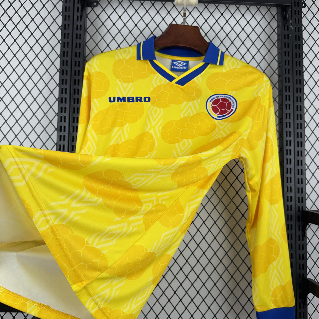 Retro Colombia home soccer jersey front, yellow with subtle geometric print, long sleeve.