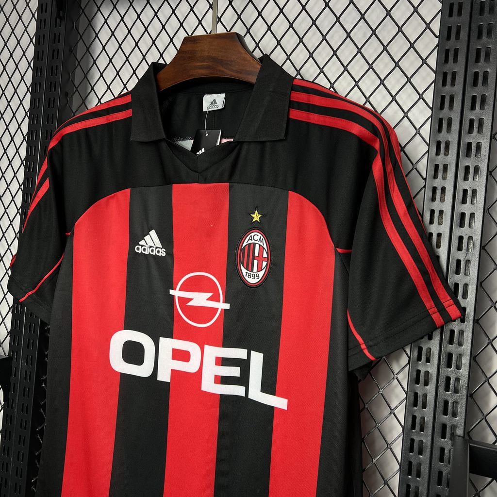 Black soccer jersey with red and black vertical stripes, Adidas logo, club crest
